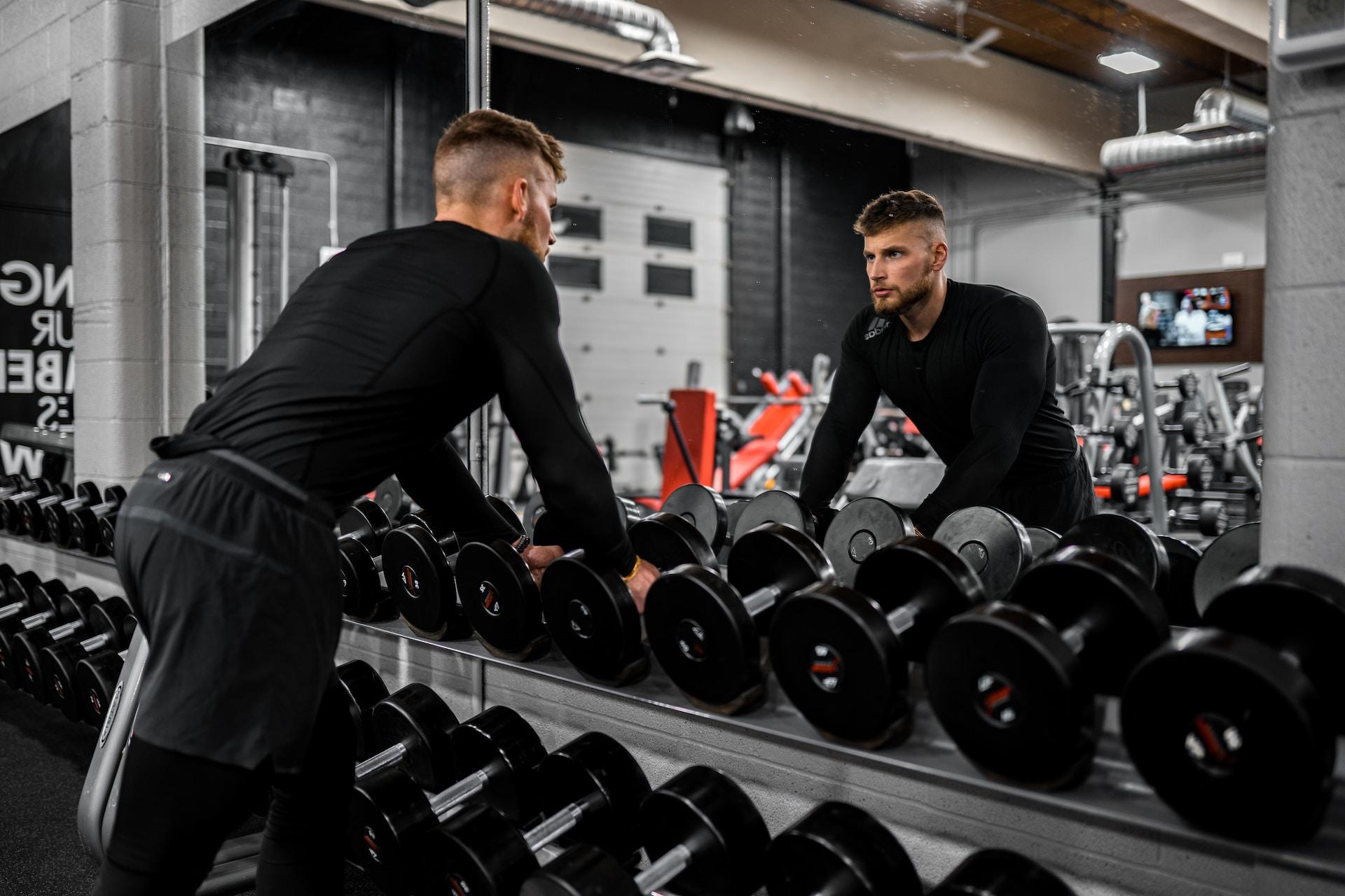 Man holding onto dumbbells on a rack.