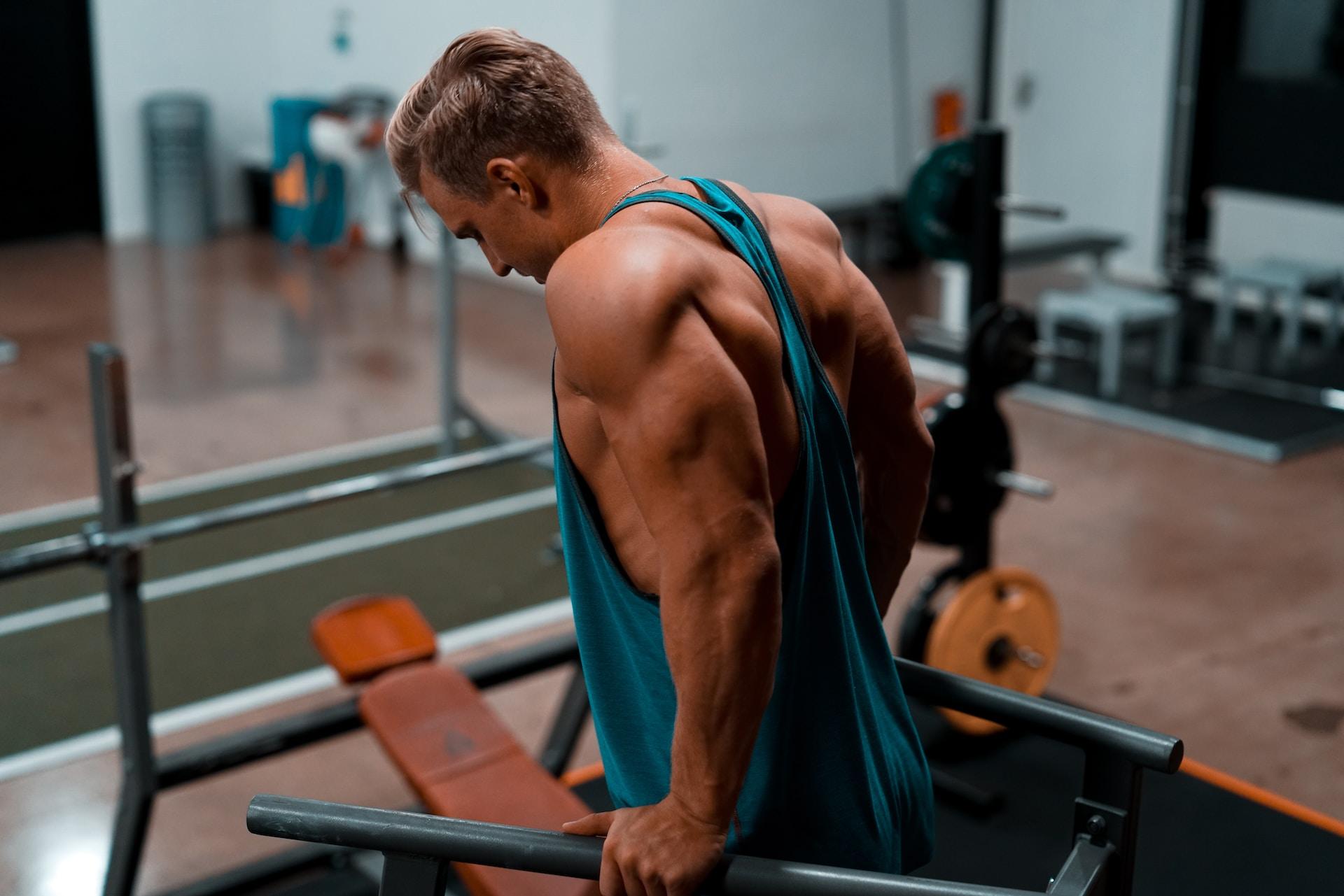 A bulky male exercising in a dip station