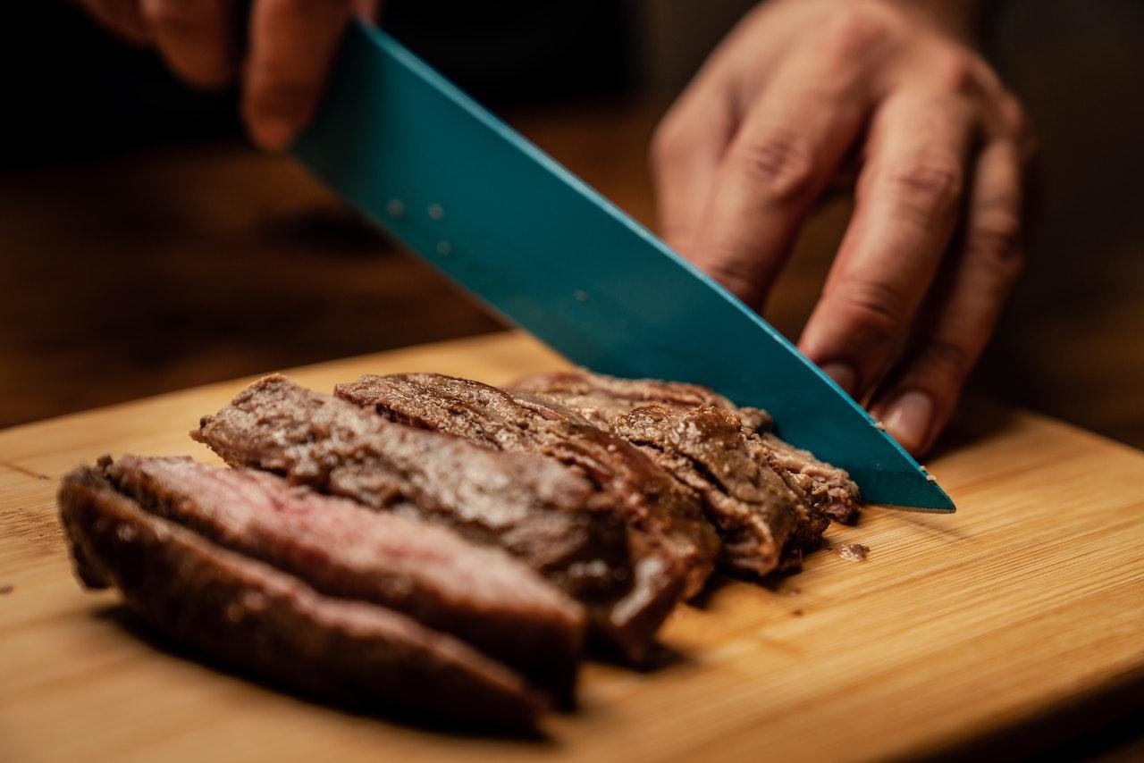 Cutting meat on a cutting board.