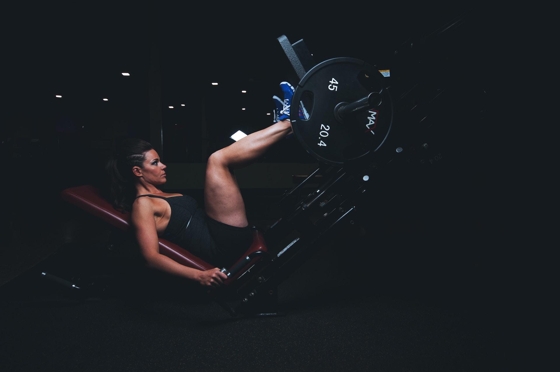 Woman using a leg press foot placement on a plate-loaded leg press machine.